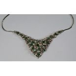 An 18ct white gold and emerald set necklace, of bib form, bright cut leaf design, set with square