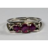 An 18ct white gold and three stone ruby ring, of stepped formation in a concave v shape setting,