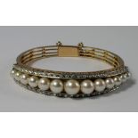 A Continental 18ct gold, pearl and diamond set hinged bangle, the shaped open work bangle set with a