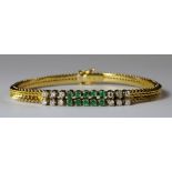 An 18ct yellow and white gold, emerald and diamond set bracelet, the two lines of stones mounted