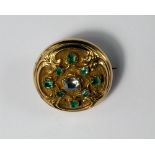 A diamond and emerald set locket brooch, 19th century, of circular form, cast scrollwork and set