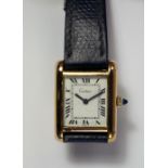 Cartier: A gold plated ladies wrist watch, with rectangular case, white dial Arabic numerals.
