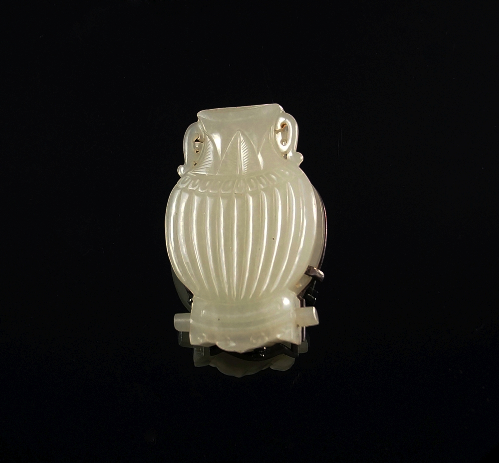 A Chinese carved pale green jade and silver mounted vase form badge,