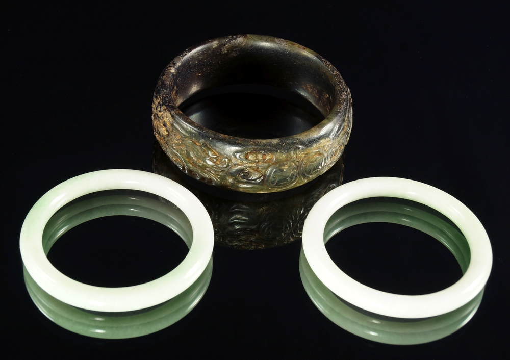 A large Chinese hardstone bangle, 19th/20th century, carved to the edge with bats and coins, 8cm