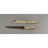 A Japanese carved bone tanto, early 20th century, carved with panels of figures, with a steel blade,