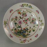 A Chinese porcelain plate, decorated with trees filled with peaches, above rock work,