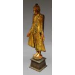 A Burmese gilt wood model of a standing Buddha, wearing a bejewelled robe,