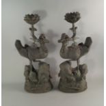 A pair of Chinese bronze models of Ducks, 20th century, modelled standing on rocks, above stylised