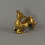A Chinese/Sino-Tibetan gilt bronze model of a deer, modelled supine on its front legs,