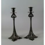 A pair of WMF Jugendstil cast candlesticks, with narrow tapering stem to a pierced whiplash square