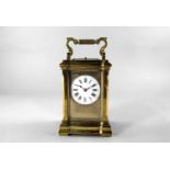 A large brass carriage clock, 20th century, with shaped case and fluted carrying handle, the