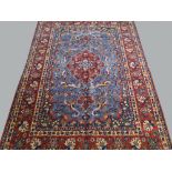 A Kashan rug with red medallion in a scroll decorated blue field, red main border,