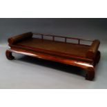 A Chinese hardwood low day bed, 20th century, with railed back, cylindrical rolling arms,