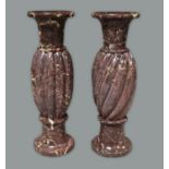 Two similar red marble long urns, 20th century, with flaring necks on lobed bodies with spreading