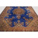 A Kirman carpet with pole medallion in a blue field, the red main border with guard stripes,