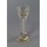 A tall drinking glass, probably 18th century, the globular bowl engraved with trailing grapes and