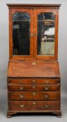A George II padouk bureau cabinet
The moulded cornice above twin mirror panelled doors enclosing