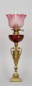 A Victorian gilt metal oil lamp
The etched red glass reservoir supported on an urn, the crimped