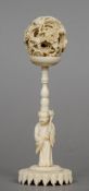 A late 19th/early 20th century carved ivory puzzle ball
Of typical form, mounted on a figurally