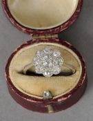 An Edwardian platinum, diamond set flowerhead ring
The central stone flanked by a row of eight