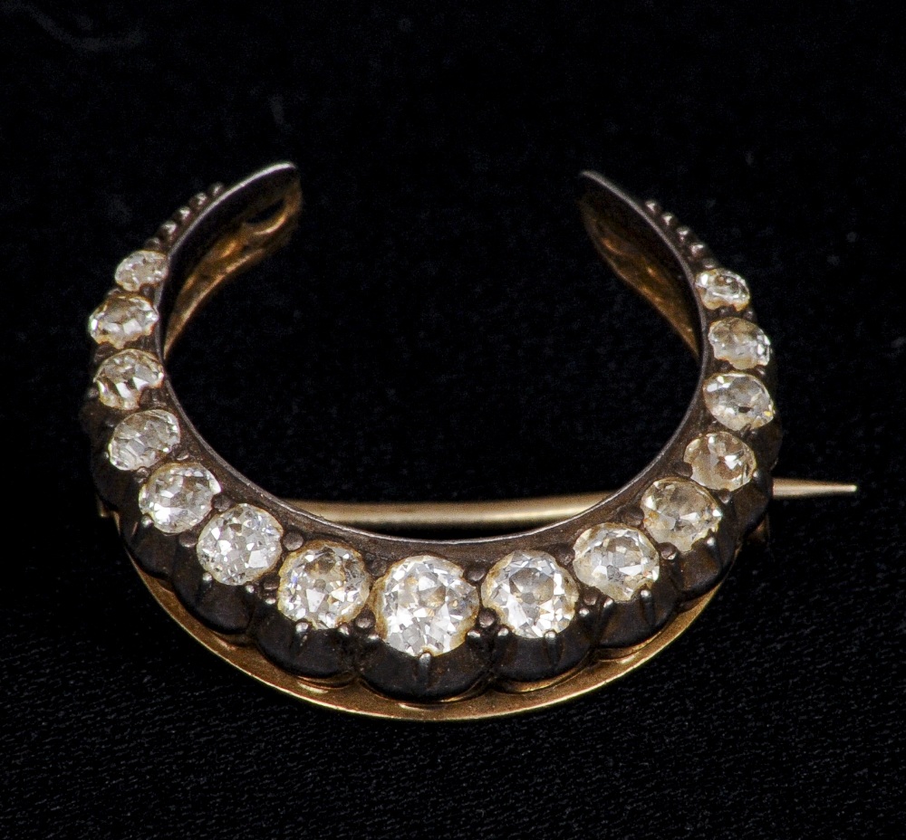 A late 19th century unmarked gold and silver, diamond set crescent brooch
Estimated total diamond