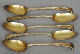 A set of five George III scroll cast silver gilt dessert spoons, three marked for London 1786, two