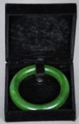 A Chinese carved green jade bangle
Of typical form, in fitted case.  8.5 cm diameter. CONDITION