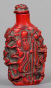 A Chinese cinnabar lacquered snuff bottle
Decorated in the round with various figures.  7.5 cm high.