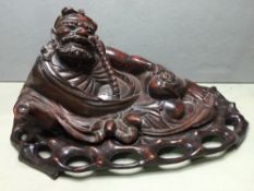 A 19th century Japanese hardwood carving
Modelled as a skinny reclining bearded man holding a gourd,