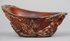 A Chinese carved horn libation type cup
Decorated in the round with figures in a tree lined