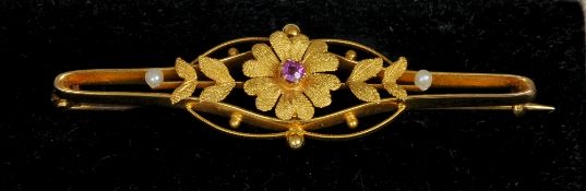 A 15 ct gold flowerhead form bar brooch
The centre red stone flanked by twin seed pearls.  5.5 cm