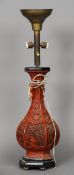 A cinnabar lacquered vase
With twin handles and floral vignettes (adapted as a lamp).  82 cm high