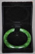 A Chinese carved green jade bangle
Of typical form, in fitted case.  9 cm diameter. CONDITION