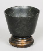 A Chinese spinach jade tea bowl
Of typical form, standing on a plinth base.  6 cm high. CONDITION