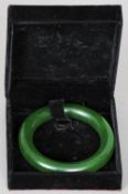 A Chinese carved green jade bangle
Of typical form, in fitted case.  9 cm diameter. CONDITION