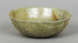 A Chinese carved green and russet jade bowl
The exterior worked with archaic script.  15 cm