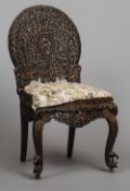 A 19th century Anglo-Indian carved hardwood chair
The ornately pierced carved back centred with a