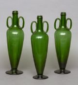 Three Italian green glass ewers
Each of tapering cylindrical form with twin loop handles, standing