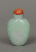 A Chinese pale apple green carved jade snuff bottle 
With red coral stopper.  6.5 cm high. CONDITION