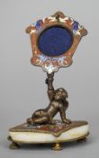 A bronze and champleve decorated pocket watch stand
Supported by a figure of a putto reclining on