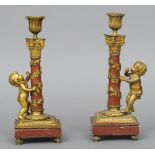 A pair of 19th century gilt metal mounted red marble candlesticks
Each flanked with a bacchic putto,