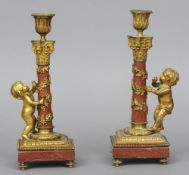 A pair of 19th century gilt metal mounted red marble candlesticks
Each flanked with a bacchic putto,