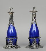 A pair of white metal mounted blue glass decanters
The mounts vine cast, both in white metal