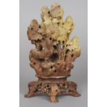 A carved soapstone group
Worked as a cockerel amongst floral sprays, standing on a carved and