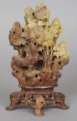 A carved soapstone group
Worked as a cockerel amongst floral sprays, standing on a carved and