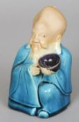 A Japanese pottery figure of Fukurokuju
Modelled seated holding a bowl.  17 cm high. CONDITION