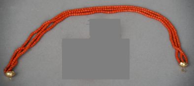 An unmarked gold mounted and coral necklace
Of three beaded strands with detachable florally