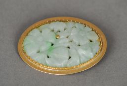 A carved jade brooch
Of pierced floral form, mounted in a gold setting, indistinctly marked to