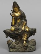A Chinese bronze and gilded figure of Guanyin
Modelled sitting atop a rocky outcrop.  18 cm high.