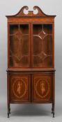 An Edwardian inlaid mahogany glazed bookcase cabinet
The broken swan-neck pediment above a bow